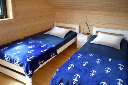 斯蒂格纳Nadmorskie Klimaty - Domki Całoroczne的配有两张床铺的客房配有蓝色床单和白色枕头