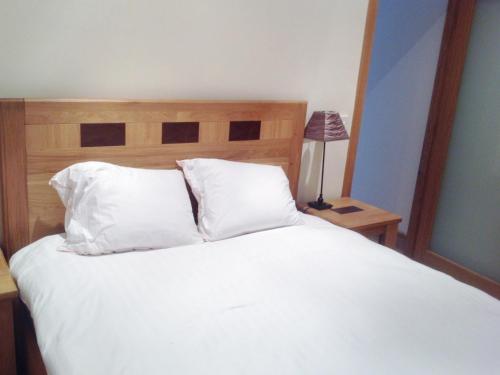 DurrusLittle Glebe Cottage的一张带白色床单和枕头的床以及一盏灯
