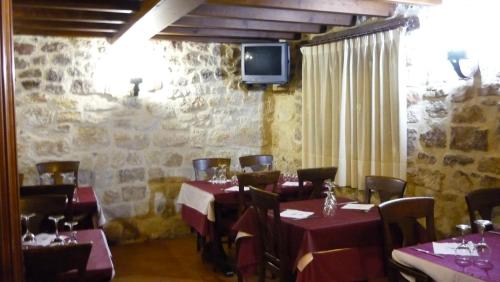 桑托多明戈德锡洛斯Hotel Rural Villa de Silos的一间带桌椅和电视的用餐室