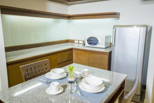 曼谷Sitara Place Serviced Apartment & Hotel的厨房配有桌子和冰箱