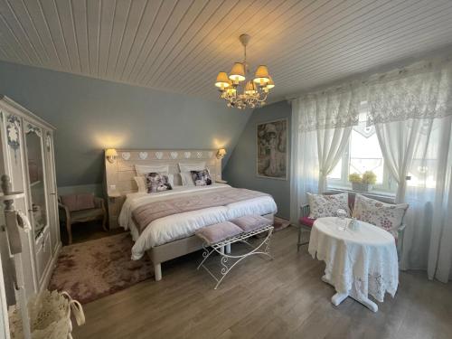 利克维Gite Riquewihr "C'est Beau la Vie Alsace"的一间卧室配有一张床、一张桌子和一个吊灯。