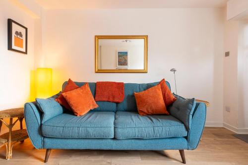 阿伯加文尼Hare Cottage的客厅里配有带橙色枕头的蓝色沙发