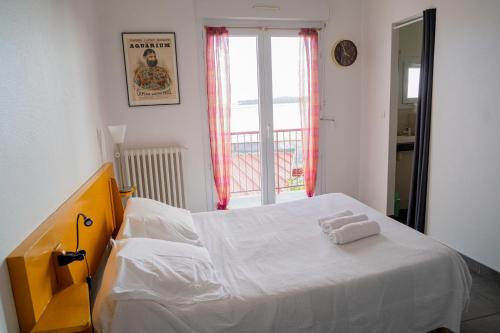 拉卡诺LE MOUTCHICO的一间卧室配有一张带白色床单的床和一扇窗户。