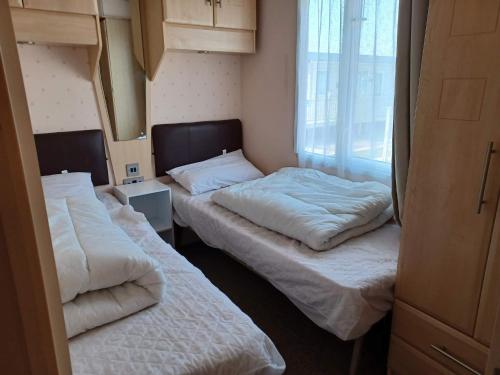 斯凯格内斯6 Berth Caravan Happy Days North Chapel St Leonards的小型客房 - 带2张床和窗户