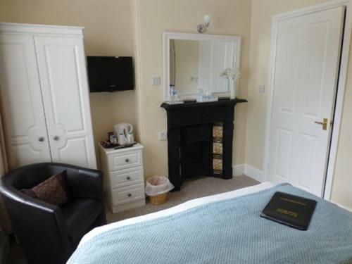 康威Bryn Derwen Guest House的一间卧室配有一张床、一把椅子和镜子