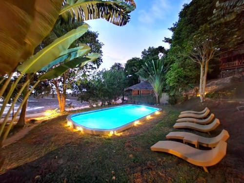俊穆岛榕树湾别墅酒店的毗邻度假酒店的带躺椅的游泳池