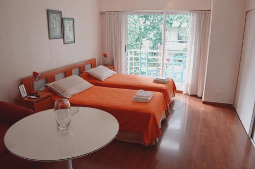 布宜诺斯艾利斯Palermo Deluxe Apartment的一间卧室设有两张床、一张桌子和一个窗口