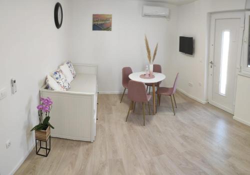 扎达尔Apartments Anamarija的白色的客房配有桌椅、桌子和桌子。