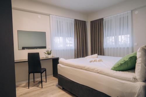 奥赫里德Bellissimo Apartments的酒店客房配有一张床、一张书桌和一台电视。