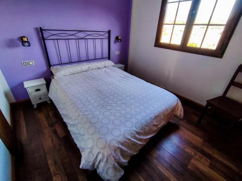 Ambas AguasA Porteliña Casa Rural的一间卧室配有一张带白色床罩的床和窗户。