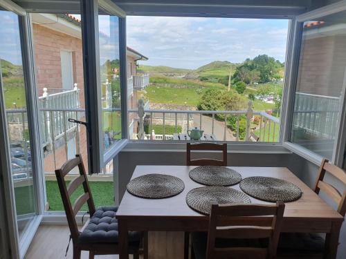 巴罗德亚尼斯Apartamento frente a la playa con vistas al mar en Barro, Llanes的一间带桌椅和大窗户的用餐室