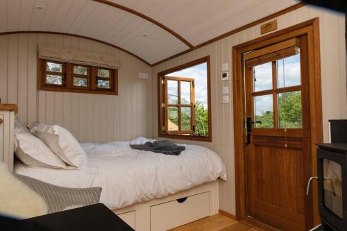 布里斯托Luxury, rural Shepherds Hut with hot tub nr Bath的一间卧室设有一张床、一台电视和窗户。