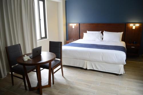 拉塔昆加Hotel San Agustin Plaza的一间卧室配有一张床和一张带笔记本电脑的桌子