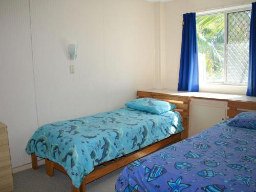 黄金海岸White Dolphin Unit 5的一间卧室设有两张床,窗户配有蓝色窗帘