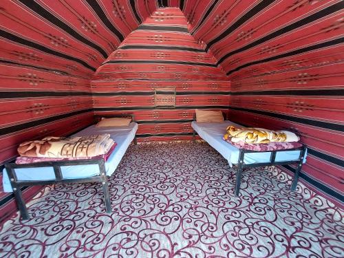 瓦迪拉姆bedouin future camp的红色墙壁上设有两张床的房间