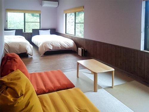 Kami玉莫诺温泉日式旅馆的客房设有两张床、一张沙发和一张桌子。