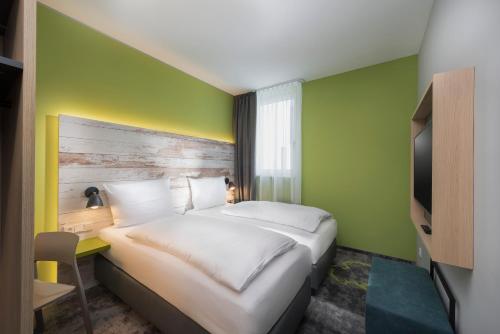 斯图加特ibis Styles Stuttgart Vaihingen的酒店客房,设有床铺和绿色的墙壁