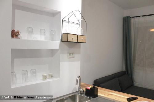 布加勒斯特Black & White - News Apartment的厨房配有水槽和带玻璃杯的架子