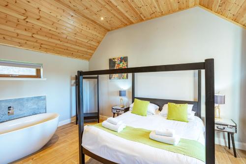 牛顿斯图尔特Kestrel Lodge 7 with Hot Tub的一间卧室设有一张大床和一个浴缸