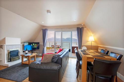 格伦科Loch Linnhe Waterfront Lodges with Hot Tubs的客厅配有桌椅和电视。