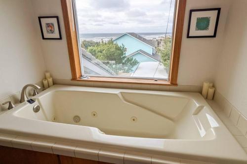 弗洛伦斯NEW Large Beach Getaway: 3 King bedroom suites!的带窗户的浴室内的白色浴缸