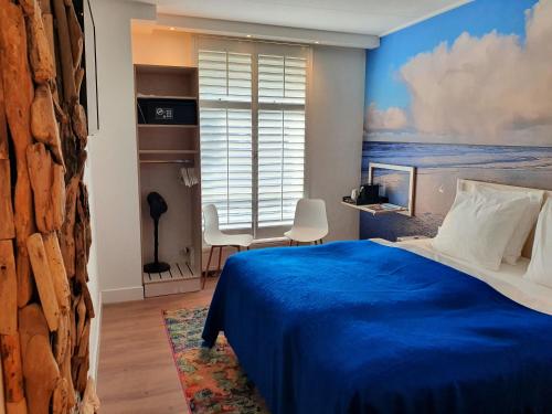 东弗利兰布鲁因拜德酒店的一间卧室设有蓝色的床和窗户。