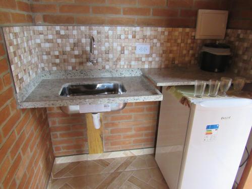 康塞高伊比蒂波卡CHALÉS DA ALÊ R do Céu nº 106的厨房柜台设有水槽和冰箱