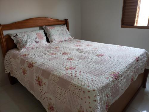奥兰布拉Loft Holambra的一张带白色粉色棉被和枕头的床