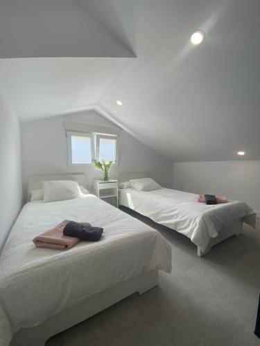 桑坦德Design Club Santander的卧室设有2张床和白色的墙壁。