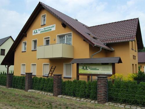 吕本Pension + Apartments Tor zum Spreewald的黄色房子前面有标志
