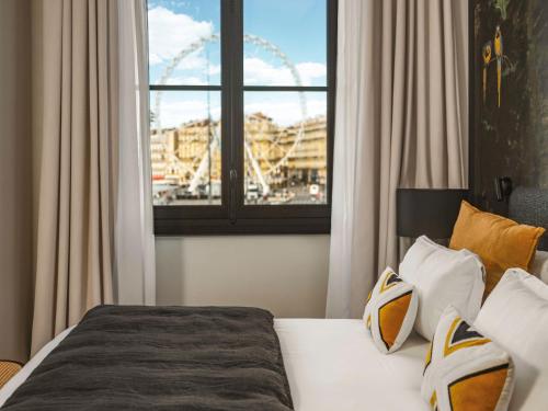 马赛Maisons du Monde Hôtel & Suites - Marseille Vieux Port的一间卧室配有一张床,享有摩天轮的景色