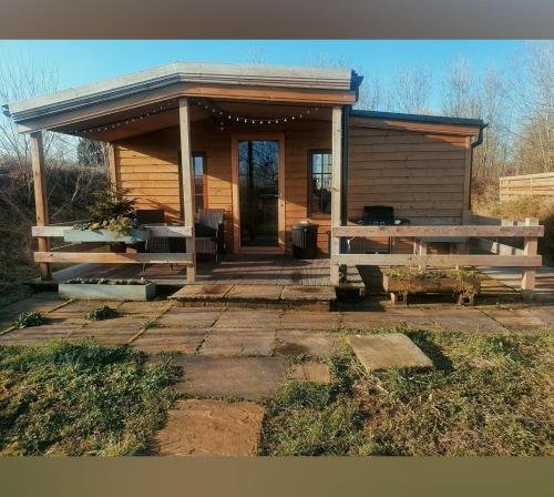 TuxfordBeautiful Wooden tiny house, Glamping cabin with hot tub 2的小屋设有门廊和桌子。