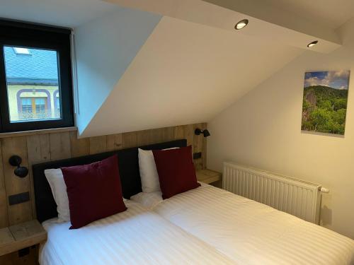 胡法利兹Rouleur Houffalize的一间卧室配有带白色床单和红色枕头的床。