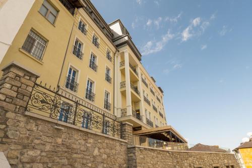 普罗夫迪夫VIZUALIZA Residence Hotel的一座大型黄色建筑,在石墙上设有阳台