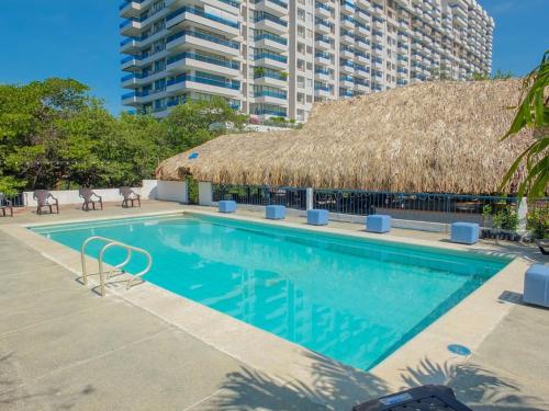 圣玛尔塔Hotel Los Veleros Santa Marta的茅草屋顶游泳池