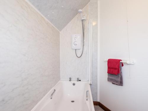 EdinbainGreshornish Boathouse的白色的浴室设有浴缸和红色毛巾。