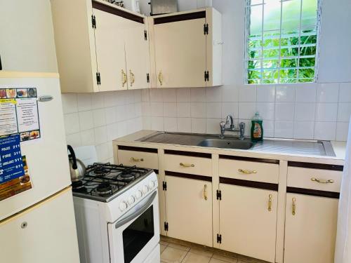 布里奇敦Ocean View Apartments的厨房配有白色橱柜和炉灶烤箱。