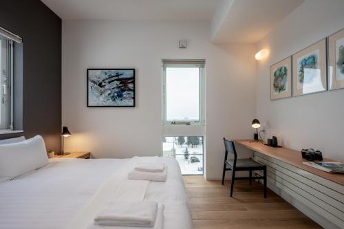 富良野Kaku Place by H2 Life的一间卧室配有一张床、一张书桌和一个窗户。