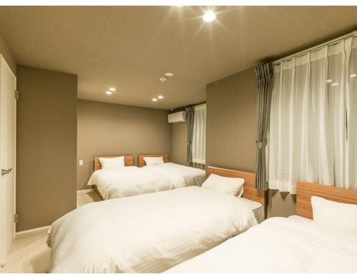 松江市Rakuten STAY HOUSE x WILL STYLE Matsue 103的一间卧室设有三张床和窗户。