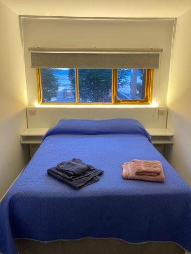 乌斯怀亚Alakalufes Estudio - Departamento completo en Ushuaia的一间卧室配有蓝色的床和2条毛巾