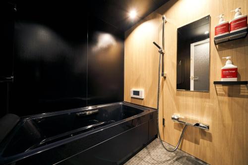 仙台Rakuten STAY x EAGLES 201 with Roof balcony的一间带黑色浴缸和镜子的浴室