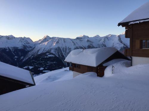 菲施Nido Alpino Fiescheralp的一座被雪覆盖的建筑,背景是群山