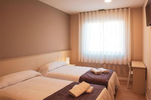 阿尔苏阿LA PUERTA DE ARZÚA的酒店客房设有两张床和窗户。