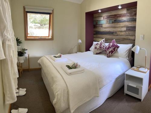 The PatchThe Mulberry Cottage的卧室配有一张白色大床和木制床头板