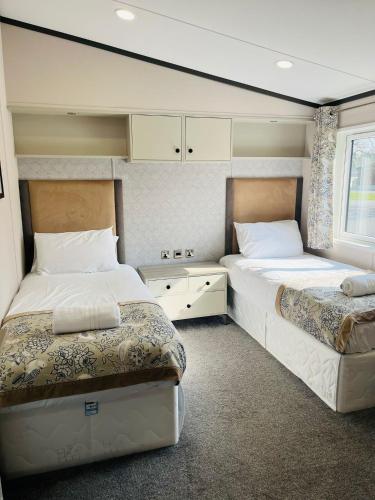 约克Brackencroft Lodge with Hot Tub的一间卧室设有两张床和窗户。