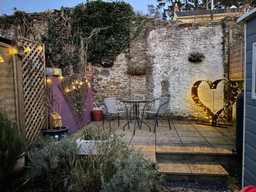 比迪福德Lotte’s Cottage的一个带桌椅和砖墙的庭院