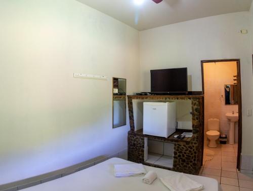 伊波兰加Pousada Casa de Pedra的客房设有床、电视和镜子