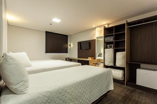 南卡希亚斯Travel Inn Axten Caxias do Sul的酒店客房设有两张床和一台平面电视。