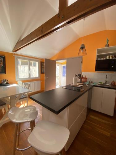 布雷斯特Le Loft brestois的厨房配有黑色台面和白色凳子
