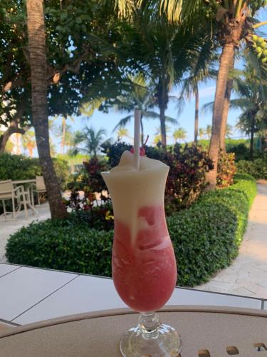 劳德代尔堡拉戈马尔海滩度假俱乐部酒店的坐在桌子上的玻璃杯里喝一杯